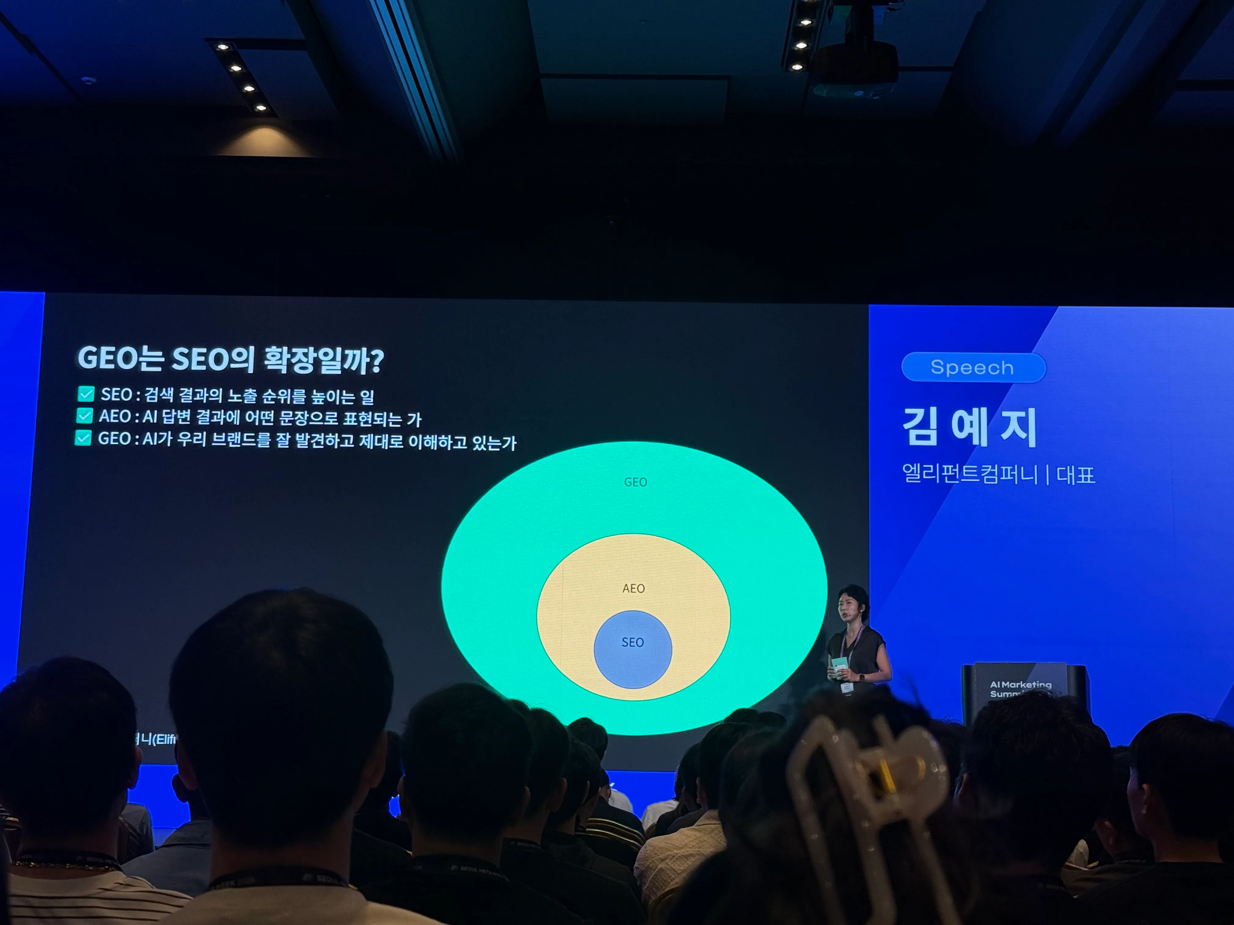 서울메타위크 AI Marketing Summit 2026 GEO 세션 현장. 발표 화면에는 “GEO는 SEO의 확장일까?”라는 제목과 함께 SEO, AEO, GEO의 관계를 설명하는 다이어그램이 보인다