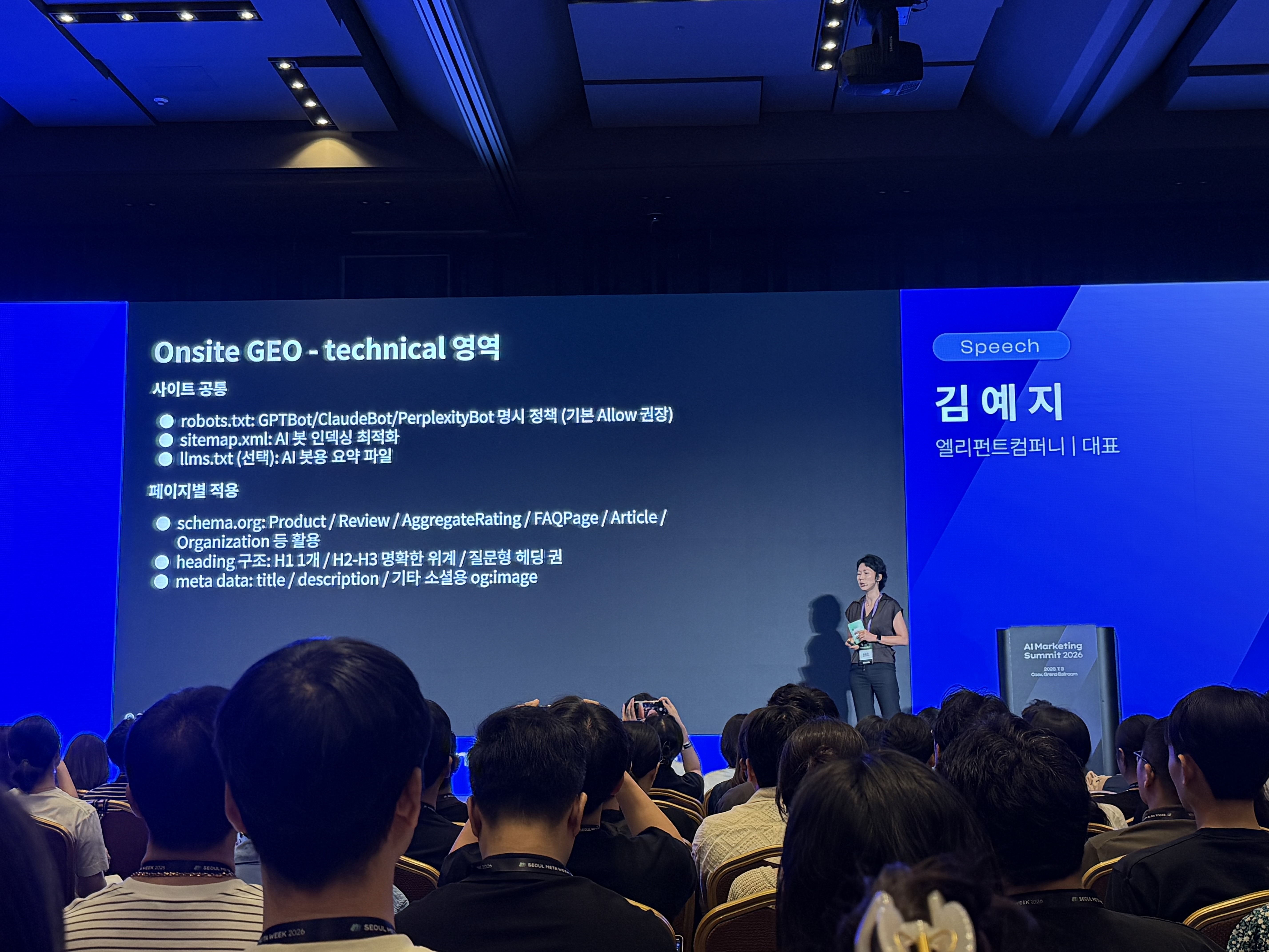 서울메타위크 AI Marketing Summit 2026 GEO 세션 현장. 발표 화면에는 “Onsite GEO - technical 영역”이라는 제목과 함께 robots.txt, sitemap.xml, llms.txt, schema.org, heading 구조, metadata 등이 정리되어 있다.